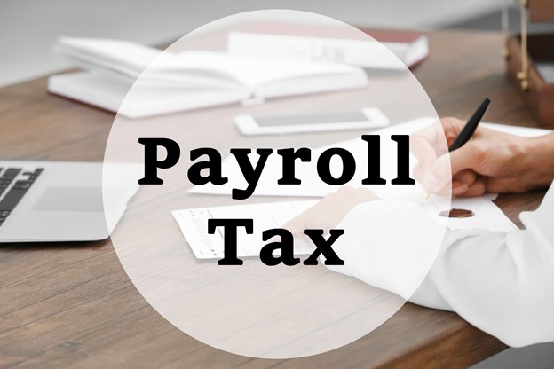 a laptop and a hand writing on a paper with a sign payroll tax